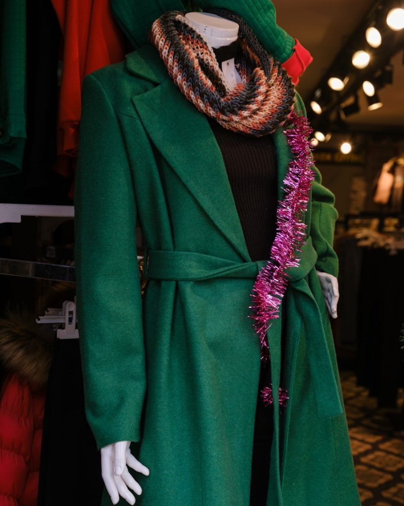 a mannequin dressed in a green coat and scarf